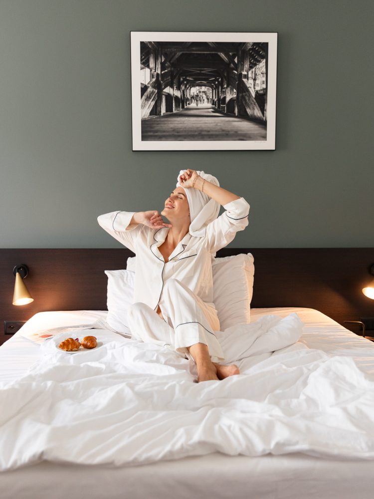 Hotelgast Frau wacht im Hotelzimmer vom Hotel Waldstätterhof Luzern auf im Bademantel
